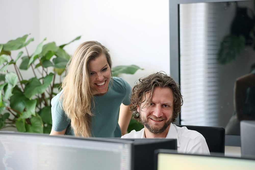 Two colleagues laughing together at a desk