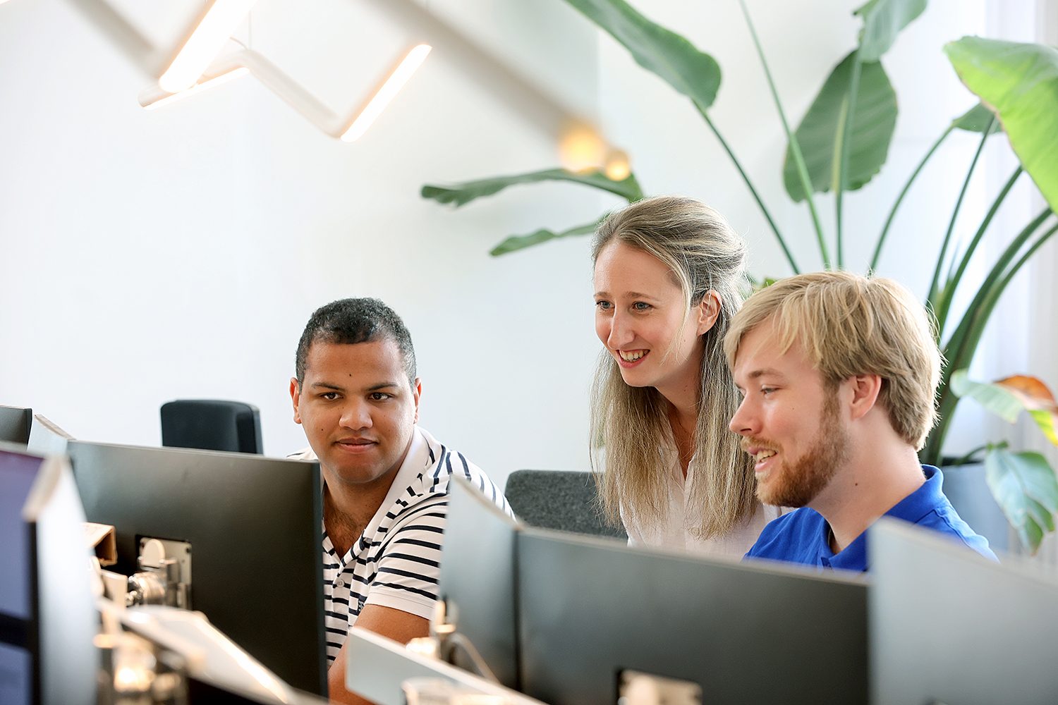 Three colleagues smiling at something on a monitor